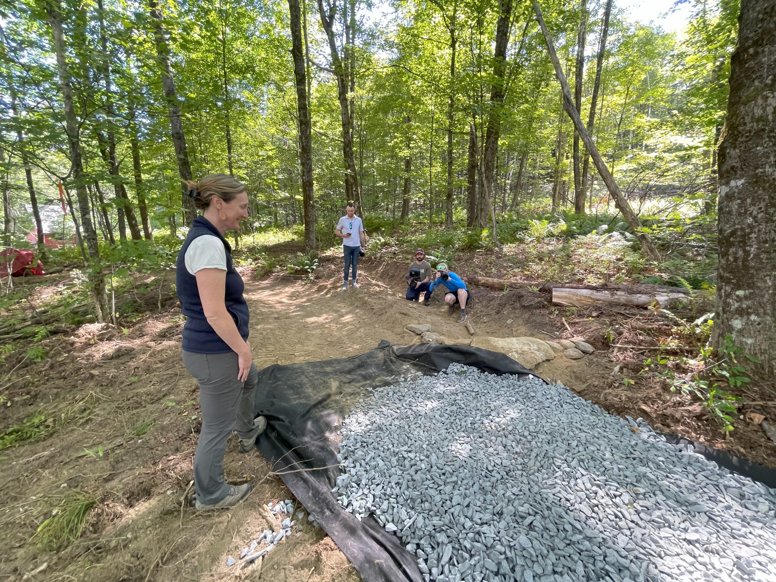 new trail being built with woman looking at fabric with gravel on top