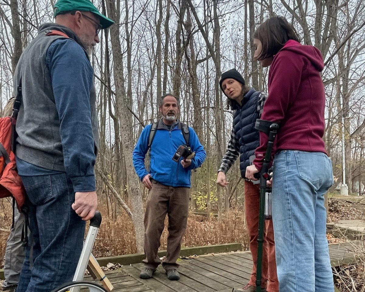 Group of people on a board walk talking about a trail and it's accessibility