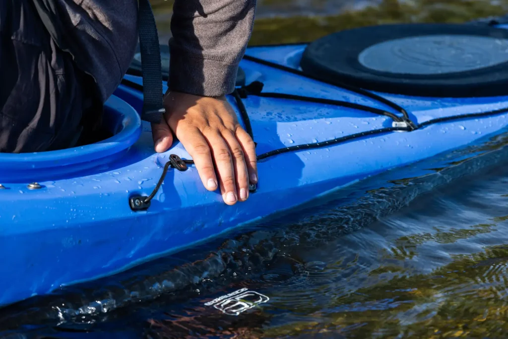 hand on blue kayak in river